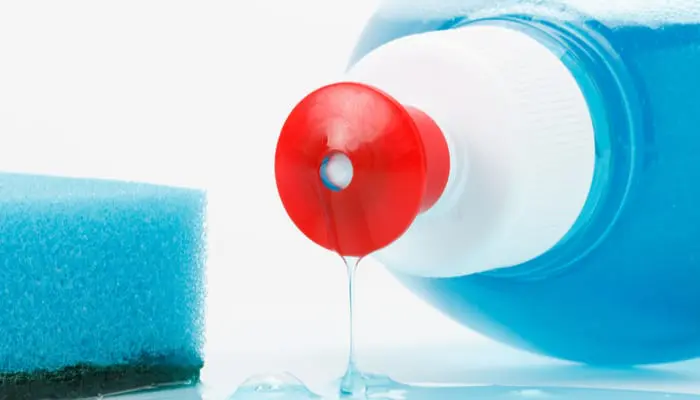 dish washing liquid flows out of the bottle, blue sponge on white