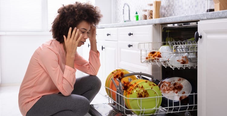 Worried Young Woman Looking At The Dirty Colorful Plates Arranged In The Dishwasher not working