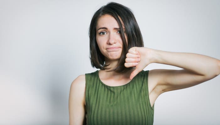 beautiful young woman showing thumbs down sign to dislike, isolated on background