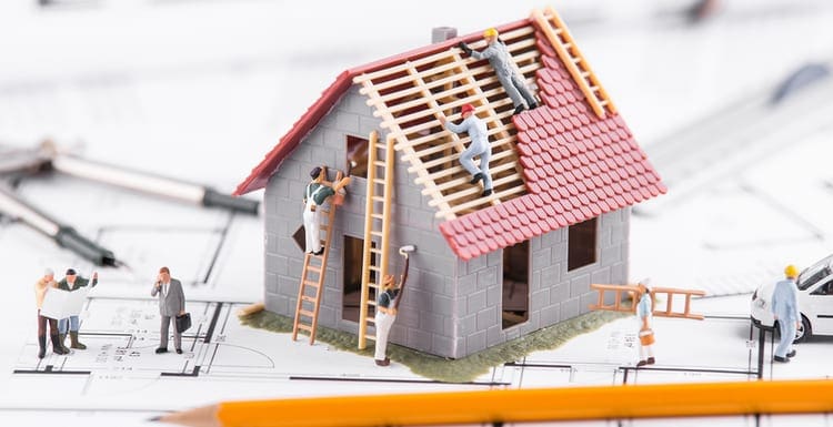 Tiny people build houses for architectural plans. The concept of teamwork.