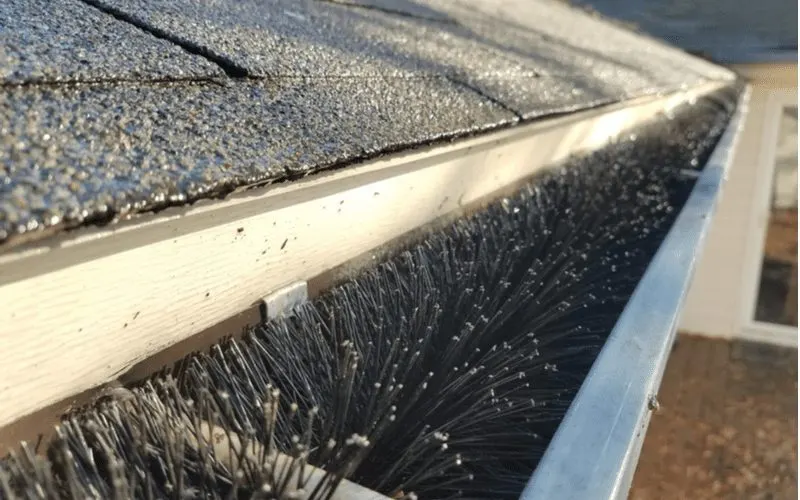 Image of the best gutter guards featuring a brush model stuck in the gutter