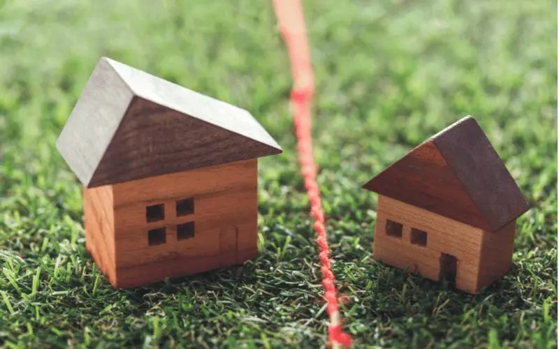 For a post on How to get a copy of your home deed, two little wooden homes sitting on a property line represented by a red string