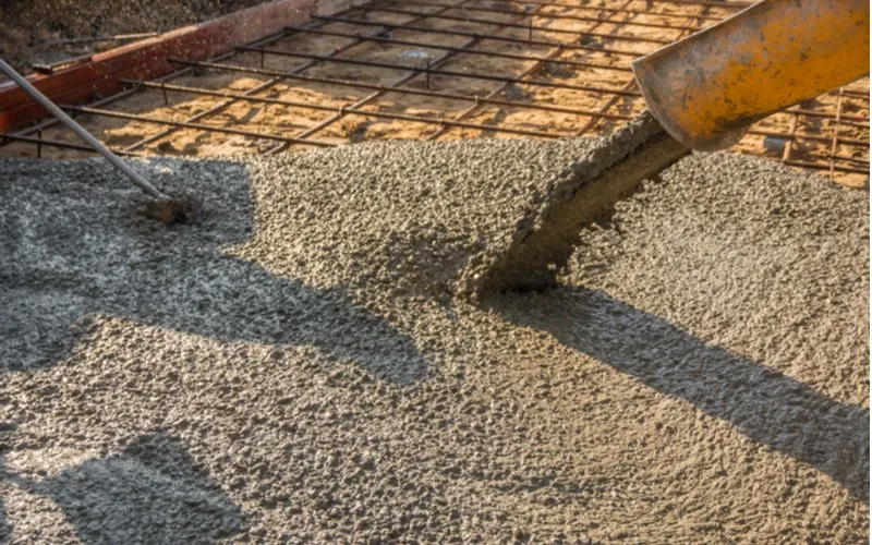 Guy pouring ready mixed concrete into a rebar-strengthened foundation