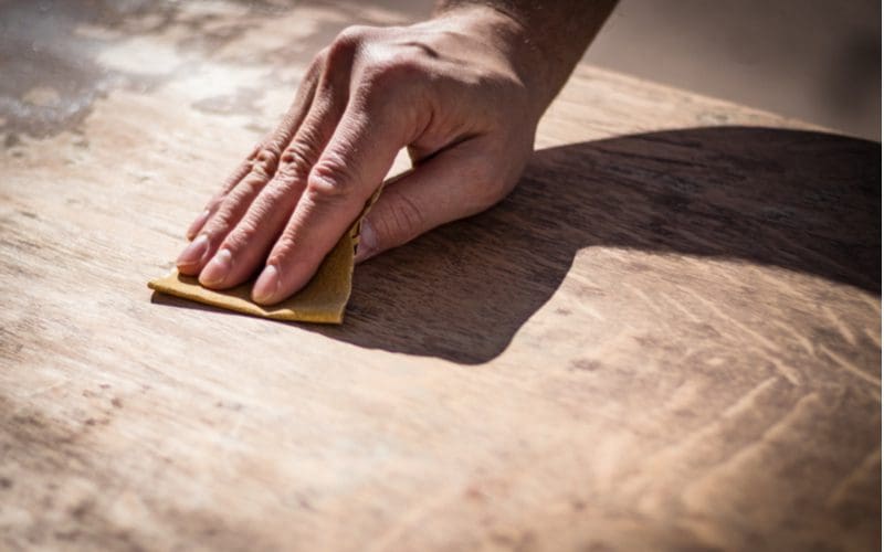 Man sanding a laminate kitchen cabinet
