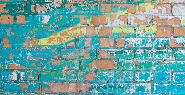 To help answer someone wondering how to remove paint from brick, a wall with cracking paint in multi colors is the featured image