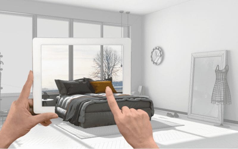 As a room design app concept, a person holds an ipad through which a virtual 3d room springs to life while she touches the pillow