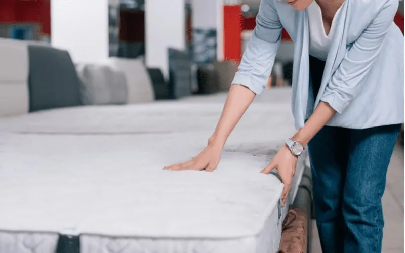 As an image for a piece on where to buy a mattress, a gal in a brick and mortar store testing the product with her hand