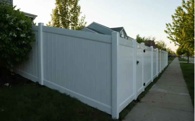 Vinyl privacy fence on a hill next to a sidewalk in a suburban neighborhood