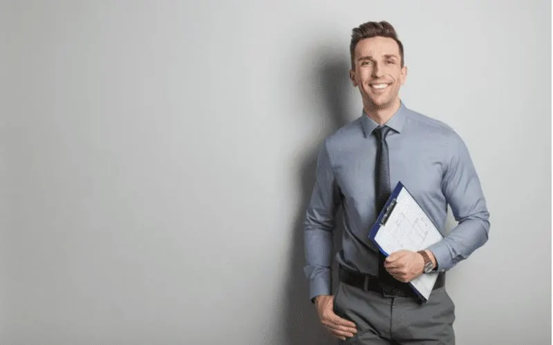 Man with a clipboard smiling for a piece on what happens if you fail the real estate exam