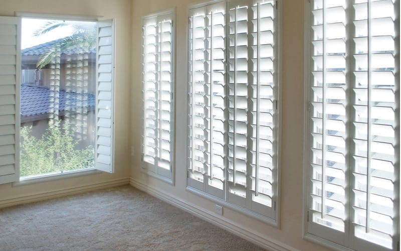 White plantation shutters in the living room of a home for a piece on plantation shutters cost