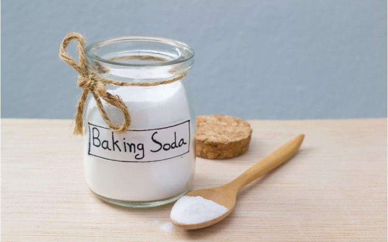 To illustrate how to unclog a double kitchen sink with standing water, a picture of sale and baking soda sits on a light wooden table in a blue room