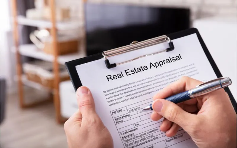 Person holding a real estate appraisal worksheet and checking boxes