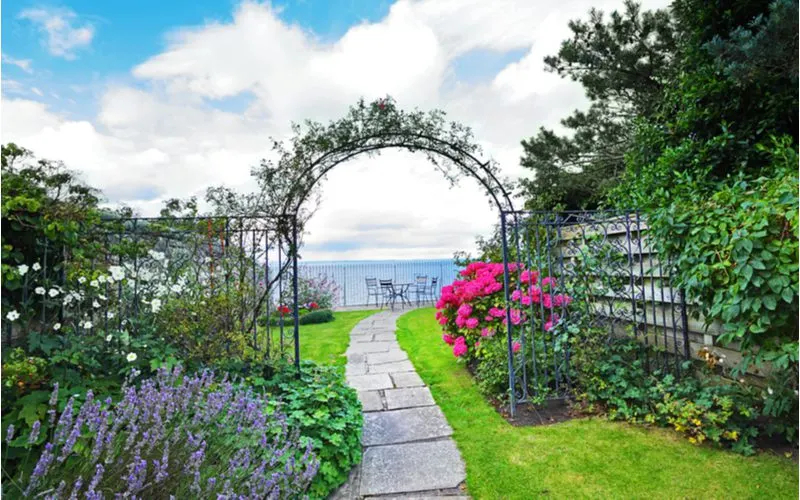 metal garden arch across a stone walkway for a piece on landscape ideas