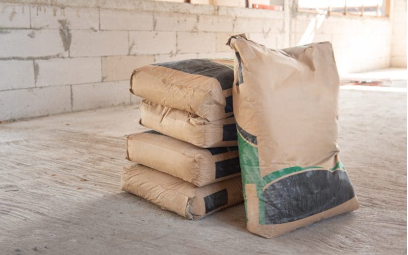 Piles of cement bags sit on a wooden floor to illustrate how much a cement patio costs