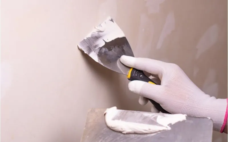 For a piece on spackle vs joint compound, a guy touches up a big hole in the wall with a putty knife