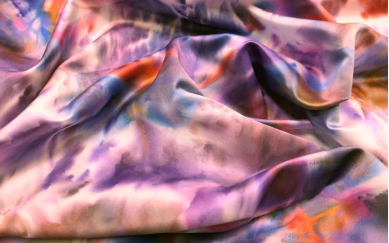 For a piece on how to dye polyester fabric, a multi-color fabric lies on the ground