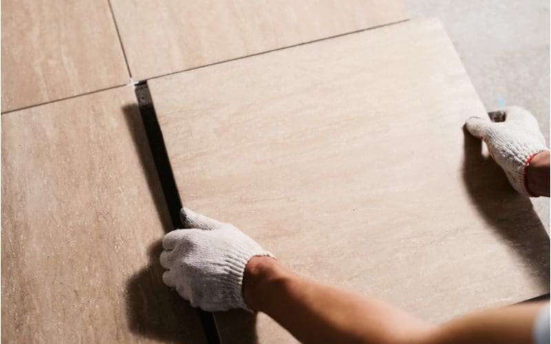 Image of a piece on sanded vs unsanded grout featuring a guy laying tile before applying the grout