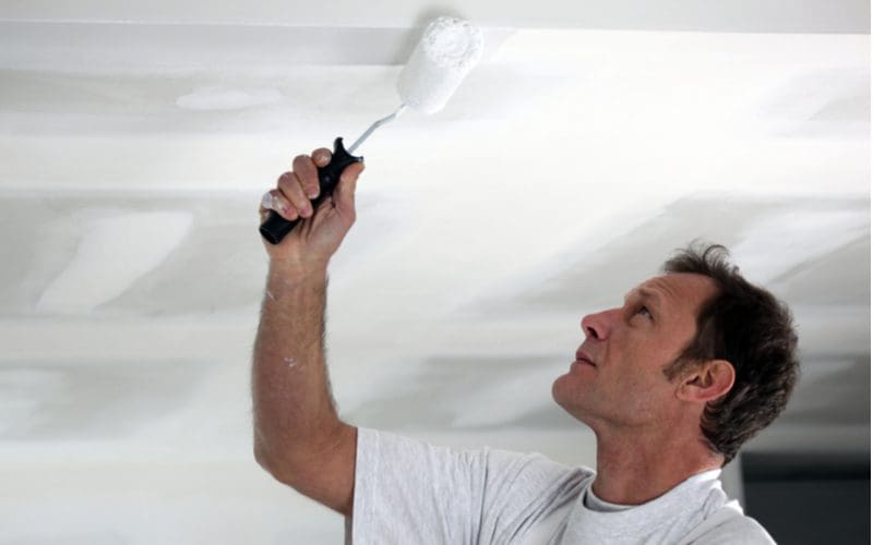 Man painting the ceiling of his garage with white satin paint
