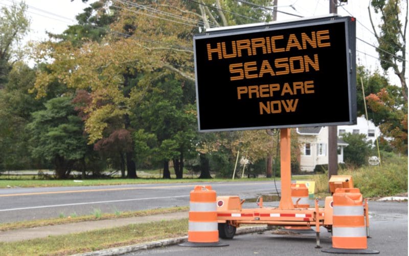 Road sign that says Hurricane Season Prepare now on the side of a tree lined road