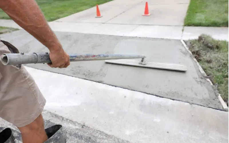 Image of a concrete driveway curing after being smoothed by a man in rubber boots