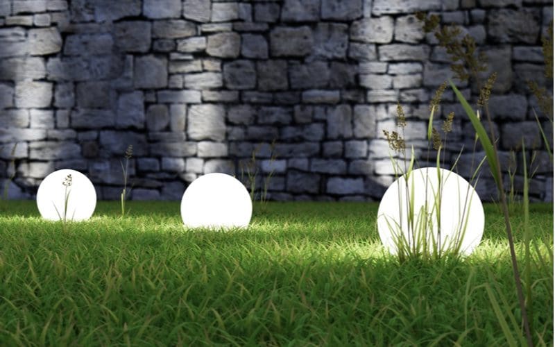 LED ball landscaping lights in grass with uplights in the background