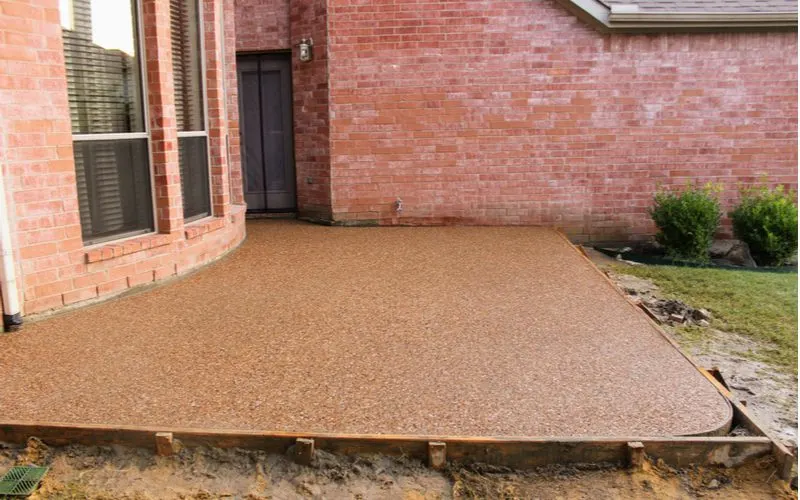 For an image on what does a concrete patio cost, a picture of a concrete slab with gravel being poured into frames
