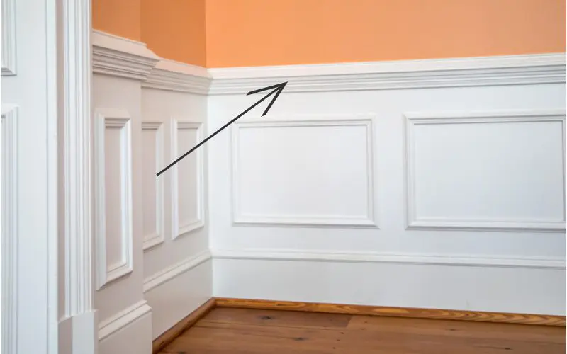 Image of a chair rail crown molding type in an orange room above wainscoating