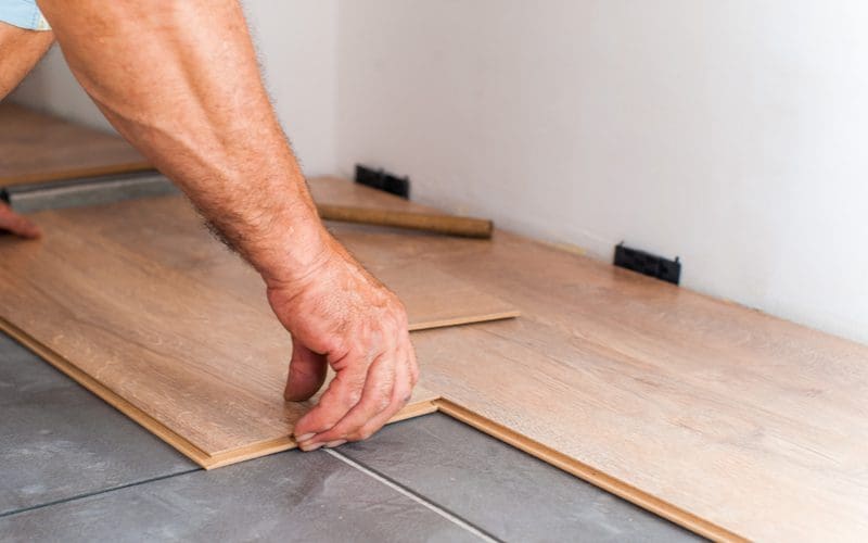 Man showing us how to install laminate flooring starting from a corner and working outward