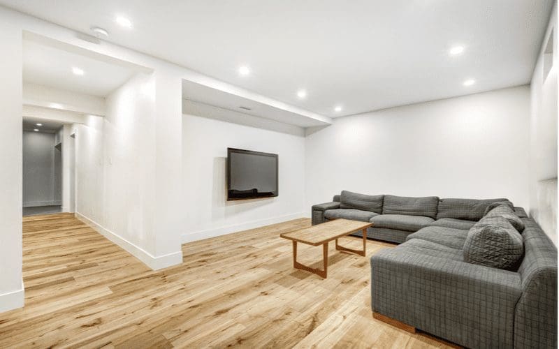 To help symbolize what'll happen if you follow our step by step guide on how to finish a basement, a finished basement with a couch and tv is all lit up