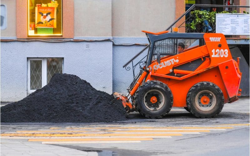 To illustrate what a cubic yard of top soil costs, a big pile of dirt in front of a skid loader