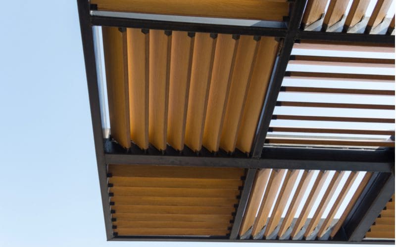 Patio shade example built out of a square metal structure with wooden slats in the middle
