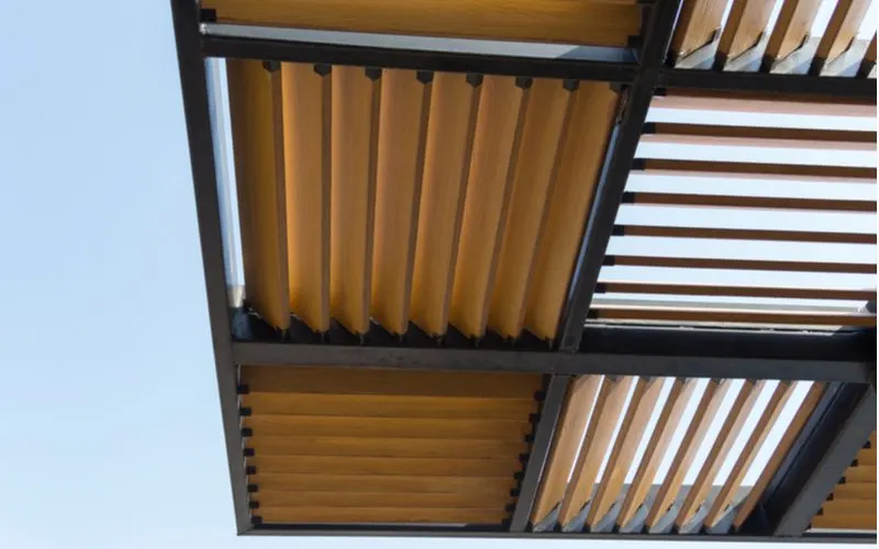 Patio shade example built out of a square metal structure with wooden slats in the middle