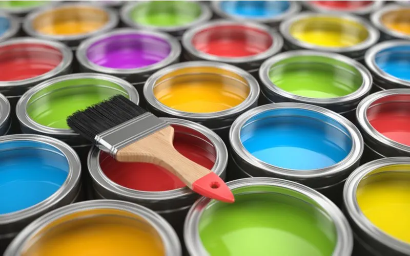 For a piece on how to paint over chrome, a bunch of paint cans with chrome tops in various colors sit below a brush
