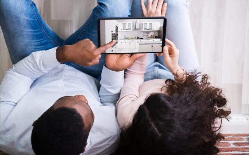 Couple planning a kitchen remodel by looking at the cost and factors affecting it on an ipad