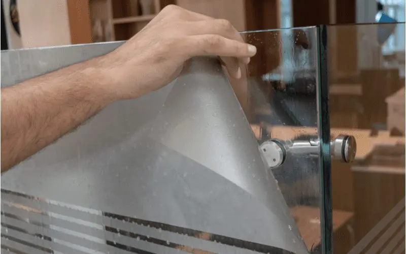 For a piece on how to frost glass, a man applying window film to a piece of glass
