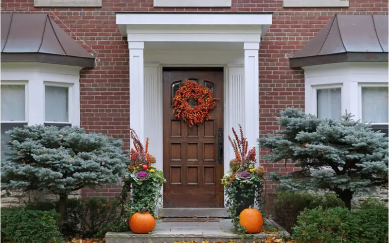 Orange fall wreath on the front door of a Colonial home