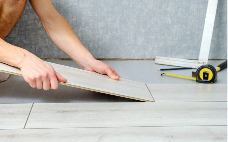 Man continuing to install laminate flooring in pieces