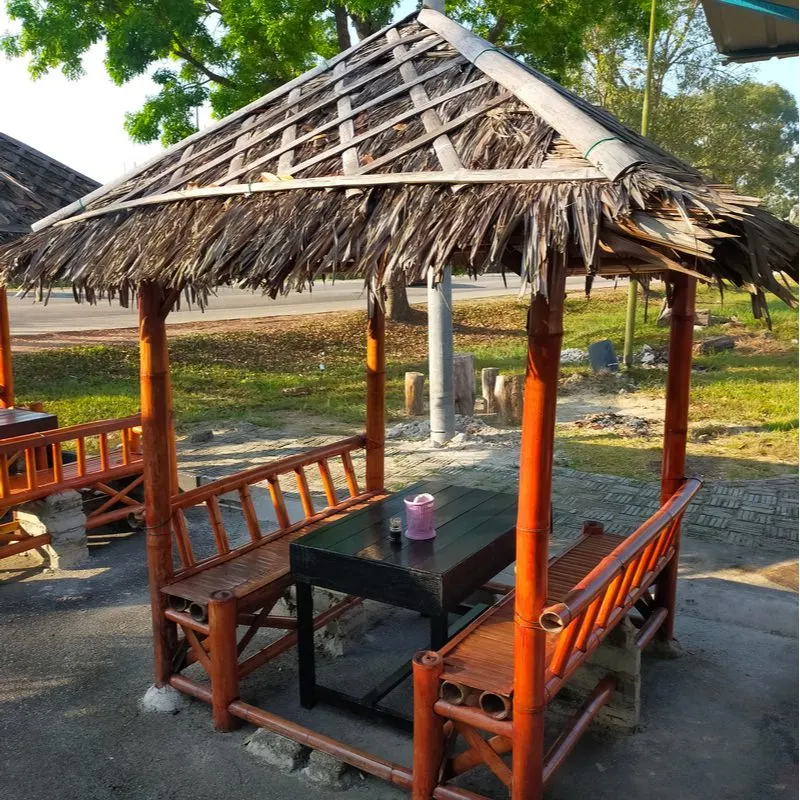 Bamboo gazebo above a simple bamboo table and booth outside a commercial buildling