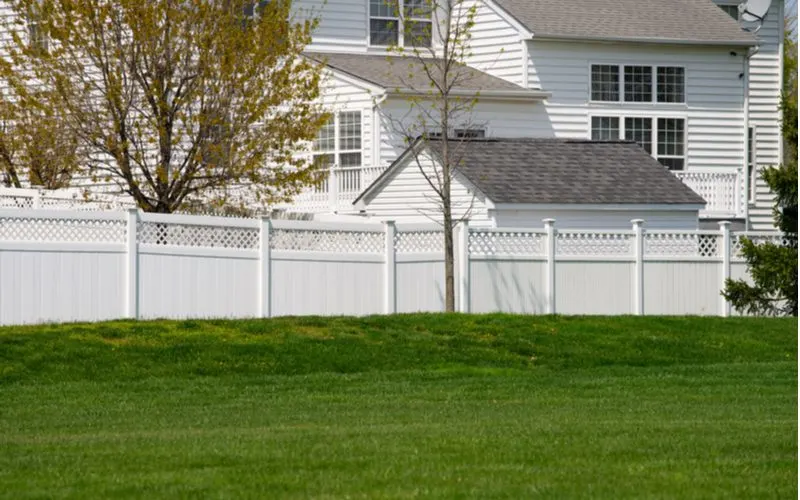 To illustrate the vinyl fence cost, a decorative and lattice privacy fence sits next to a white vinyl home