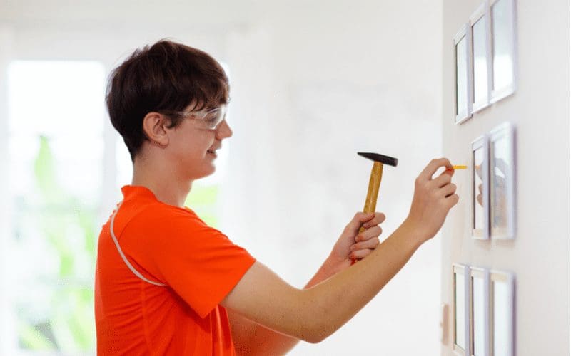 Image of a man hammering a drywall anchor through the wall