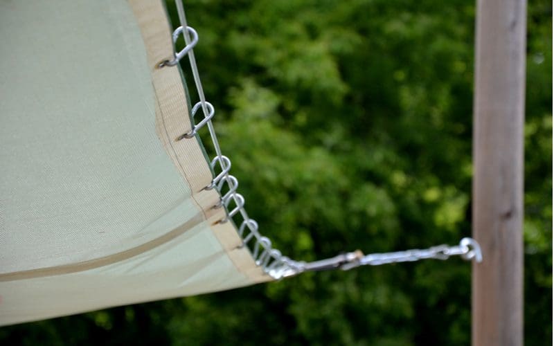Simple patio shade tarp attached to two wooden poles with wire