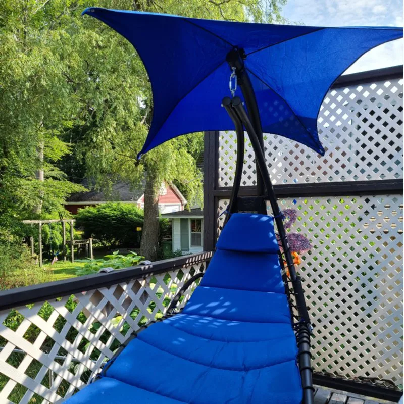 Blue swing hammock in a crazy blue color with a tilted umbrella next to a lattice railing