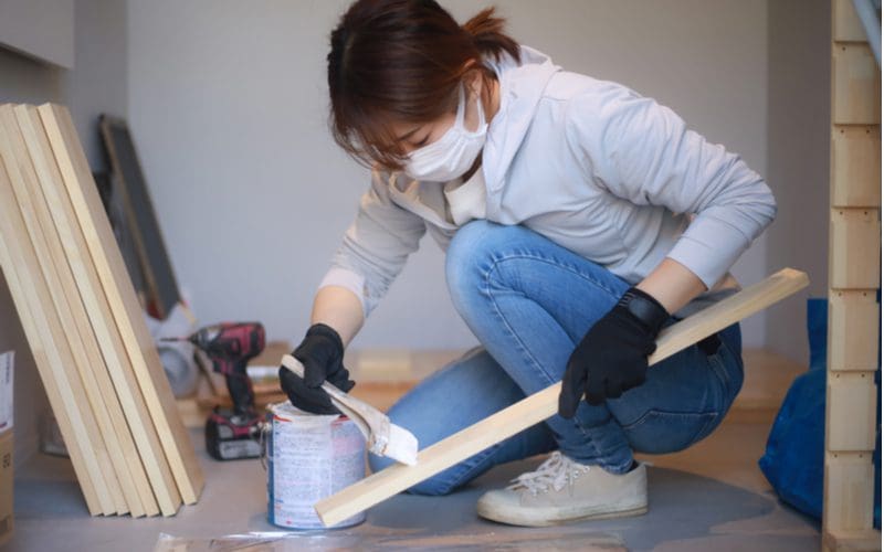 Woman painting over primed wood that's pressure treated