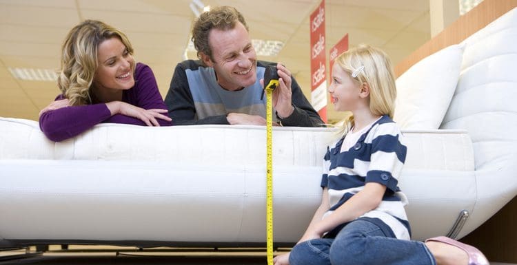Young couple measuring the bed height in a furniture store while their daughter sits on the ground