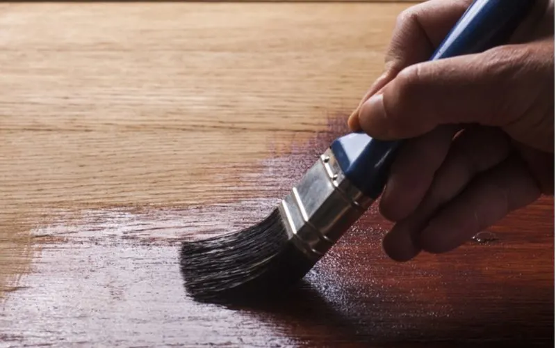To answer can you paint over stain, a paint brush pulling paint down a piece of already stained wood