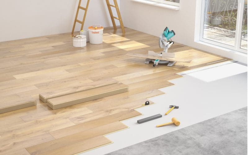 Step 8 in a guide on how to install laminate flooring showing a workspace with a saw to get the last piece down to the end