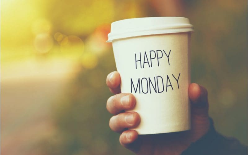 Person holding a coffee cup that says Happy Monday because that's the best day of the week to buy a house