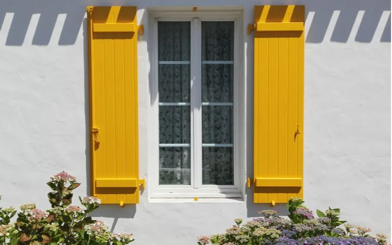 Yellow painted shutters on the outside of a white stucco house as an idea to boost curb appeal