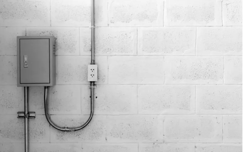 Check the panel to fix sprinklers that won't turn off featuring a simple white wall with conduit and a grey panel