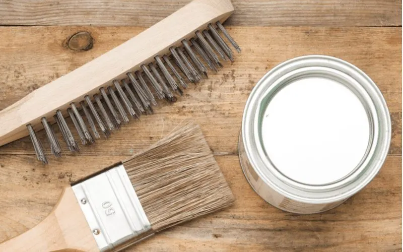 Materials needed to remove paint from wood including a wire brush, print brush, and a can of stripper